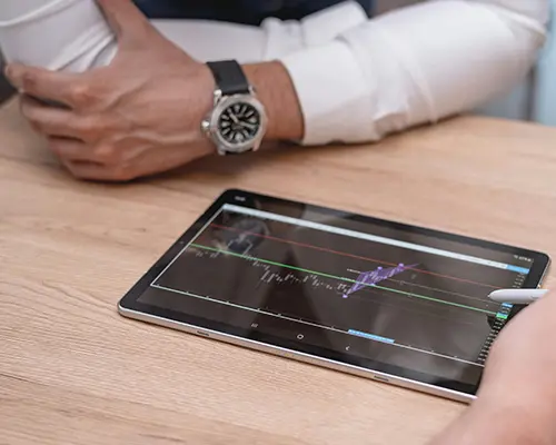 Person analysing a tablet displaying financial or pricing data with graphs.
