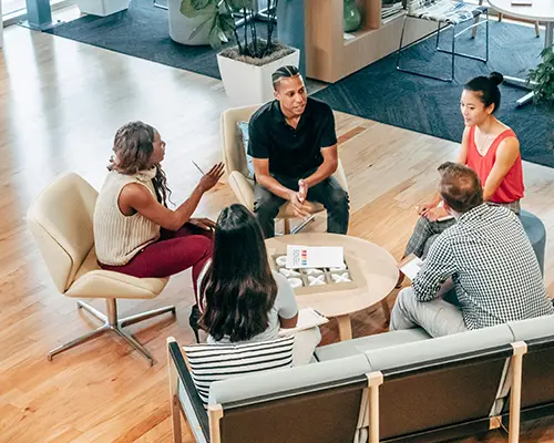 Group of diverse professionals engaged in an informal discussion in a modern office setting.