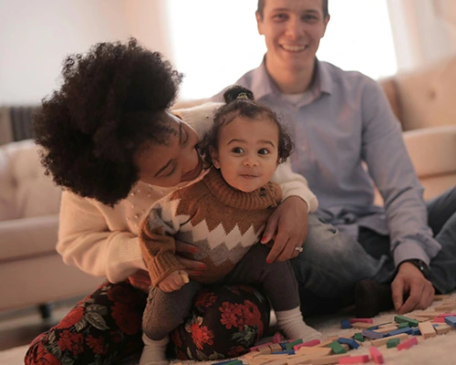 Happy young family playing with building blocks on the floor of their living room.