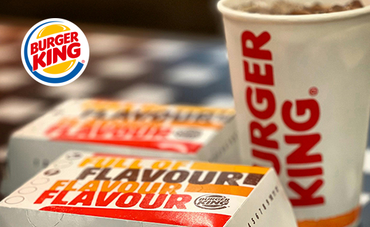Close-up of Burger King burger boxes labeled “Full of Flavour” next to a branded drink cup.