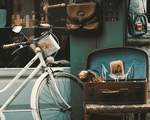 Vintage bicycle and suitcase with an old photograph outside a retro shop.