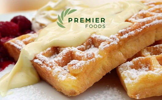 Golden waffles topped with vanilla custard and icing sugar, served with raspberries, with Premier Foods logo.