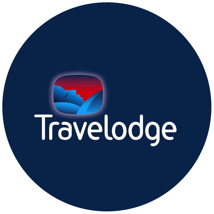 Travelodge logo featuring a stylized image of a sleeping figure in blue and red tones above the word “Travelodge” in white text on a dark blue background.
