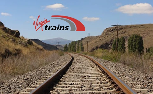 Railway track stretching through a rural valley with blue skies and distant hills, Virgin Trains logo above.