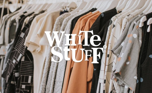 Assorted patterned and plain garments on hangers in a White Stuff clothing store.