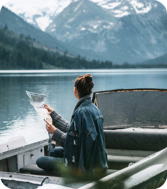 Woman in a boat on a peaceful mountain lake looking at a map