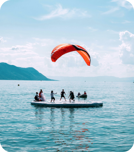 Group of people helping someone paraglide on a calm sea