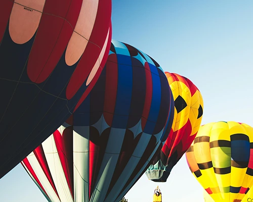 Colorful hot air balloons rising into a clear blue sky.